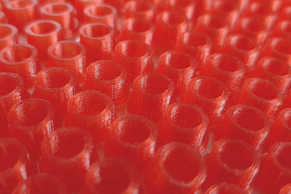 Charge gleicher Bauteile aus rotem Filament, im FDM-Verfahren gedruckt
